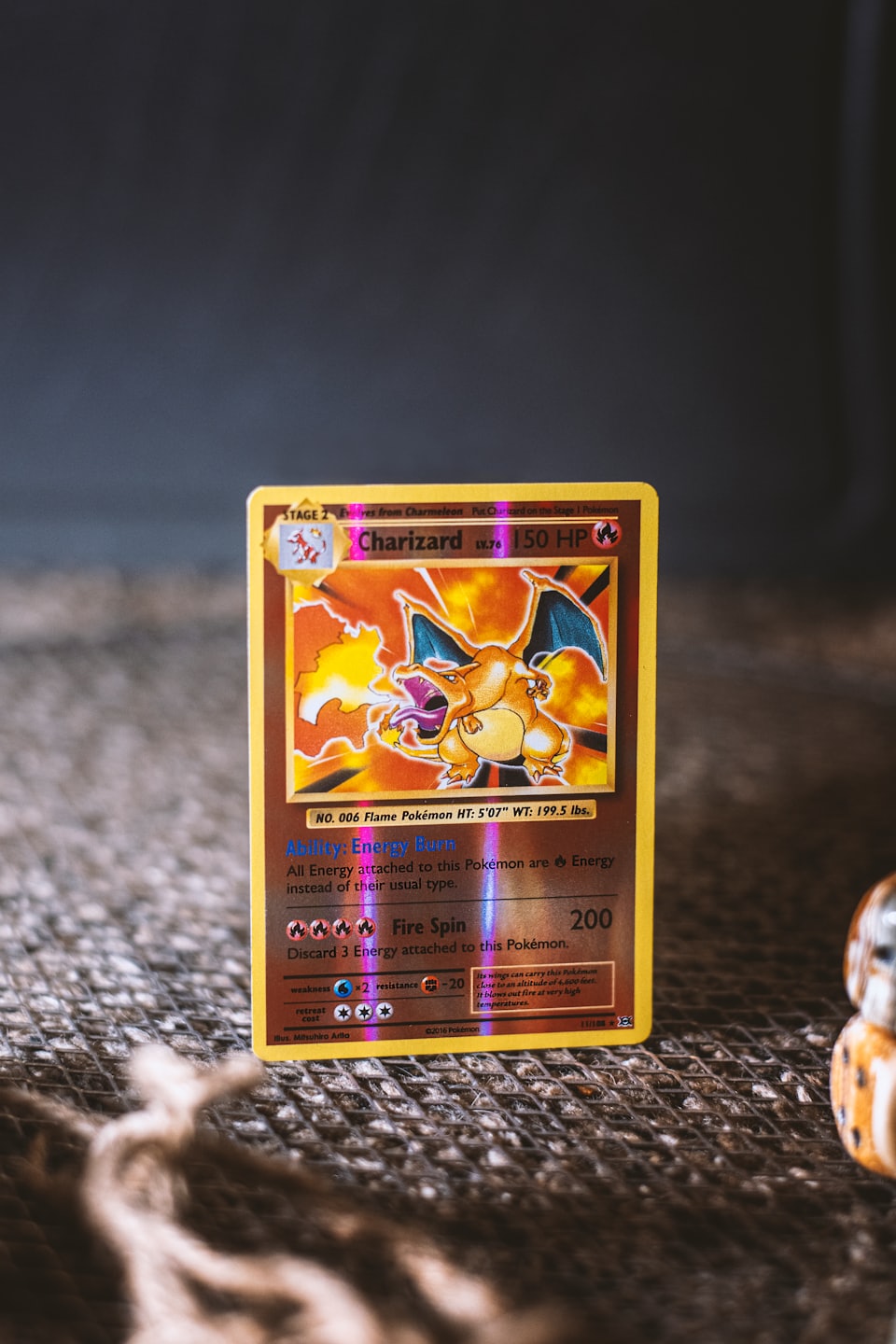 Holografisk Charizard Pokémon-kort på en brun vävd yta.