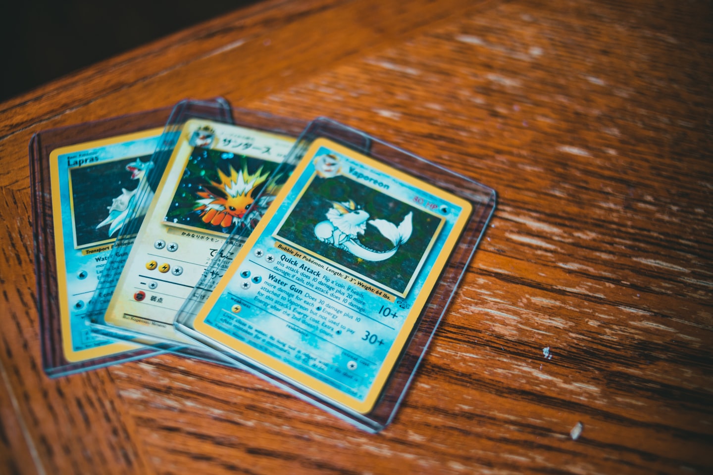 Tre vintage Pokémon-kort upplagda på ett träbord.