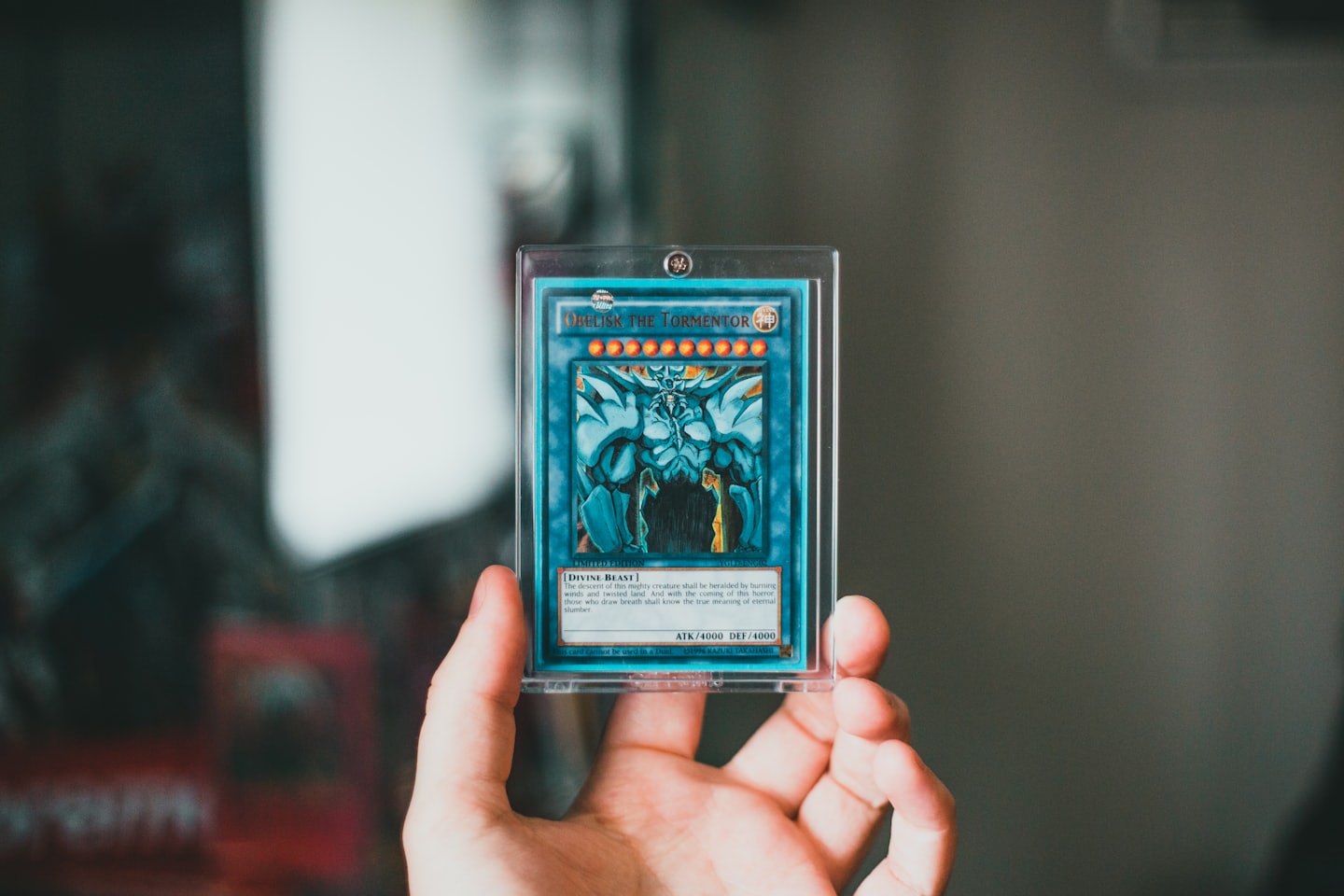 En hand håller ett Yu-Gi-Oh Obelisk the Tormentor-samlarkort.